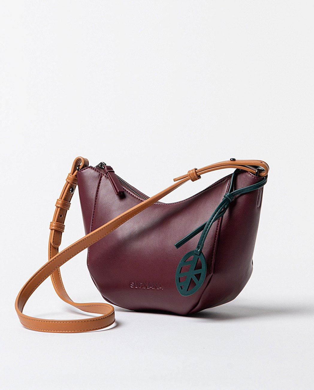 Curved bordeaux faux leather shoulder bag, with printed interior and adjustable handle in contrasting orange color, closes with a top zipper.
