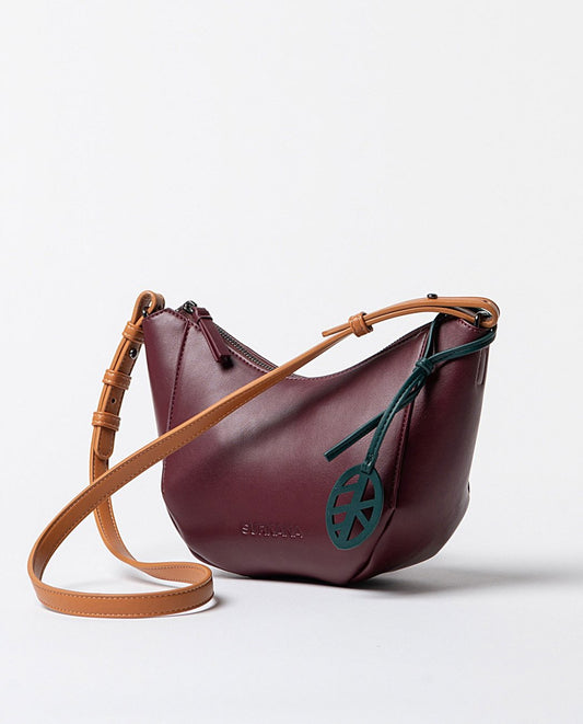 Curved bordeaux faux leather shoulder bag, with printed interior and adjustable handle in contrasting orange color, closes with a top zipper.