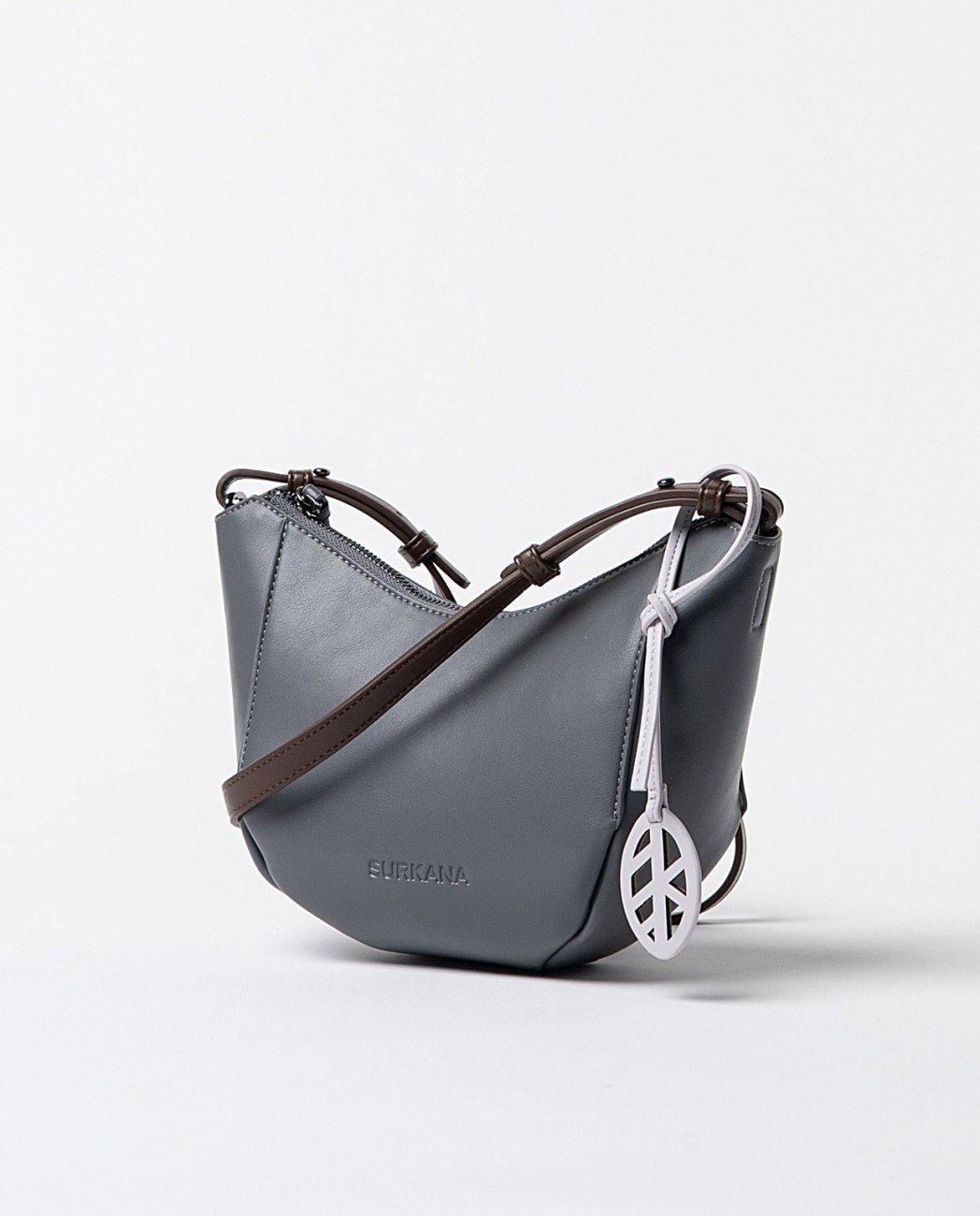 Curved grey faux leather shoulder bag with printed interior, adjustable handle in contrasting brown color, closes with a top zipper.