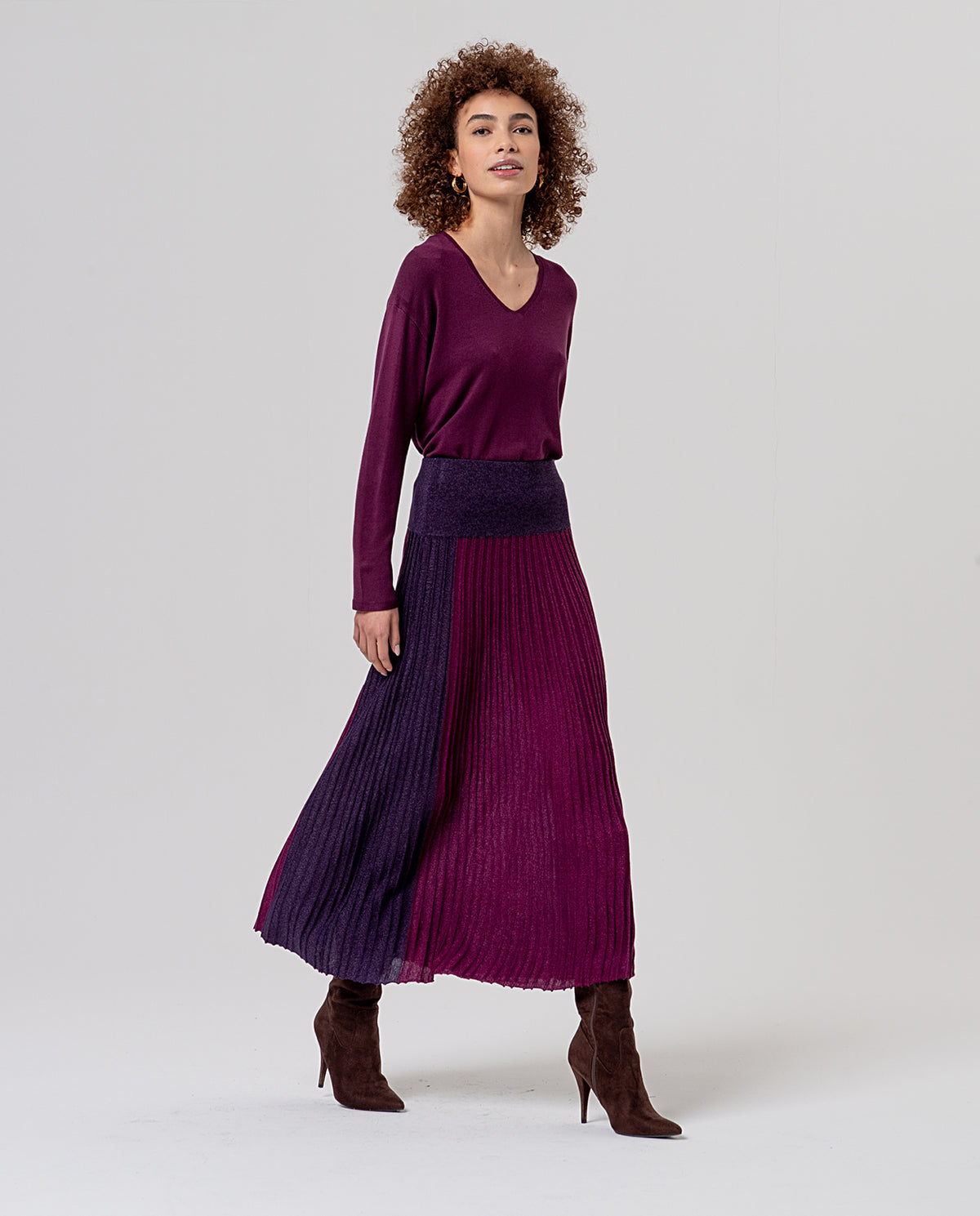 Pleated midi skirt with a lurex shimmer and elastic waist. Colour-block design pairing a central bordeaux panel with darker burgundy side sections. Light, full of movement and a festive glow.