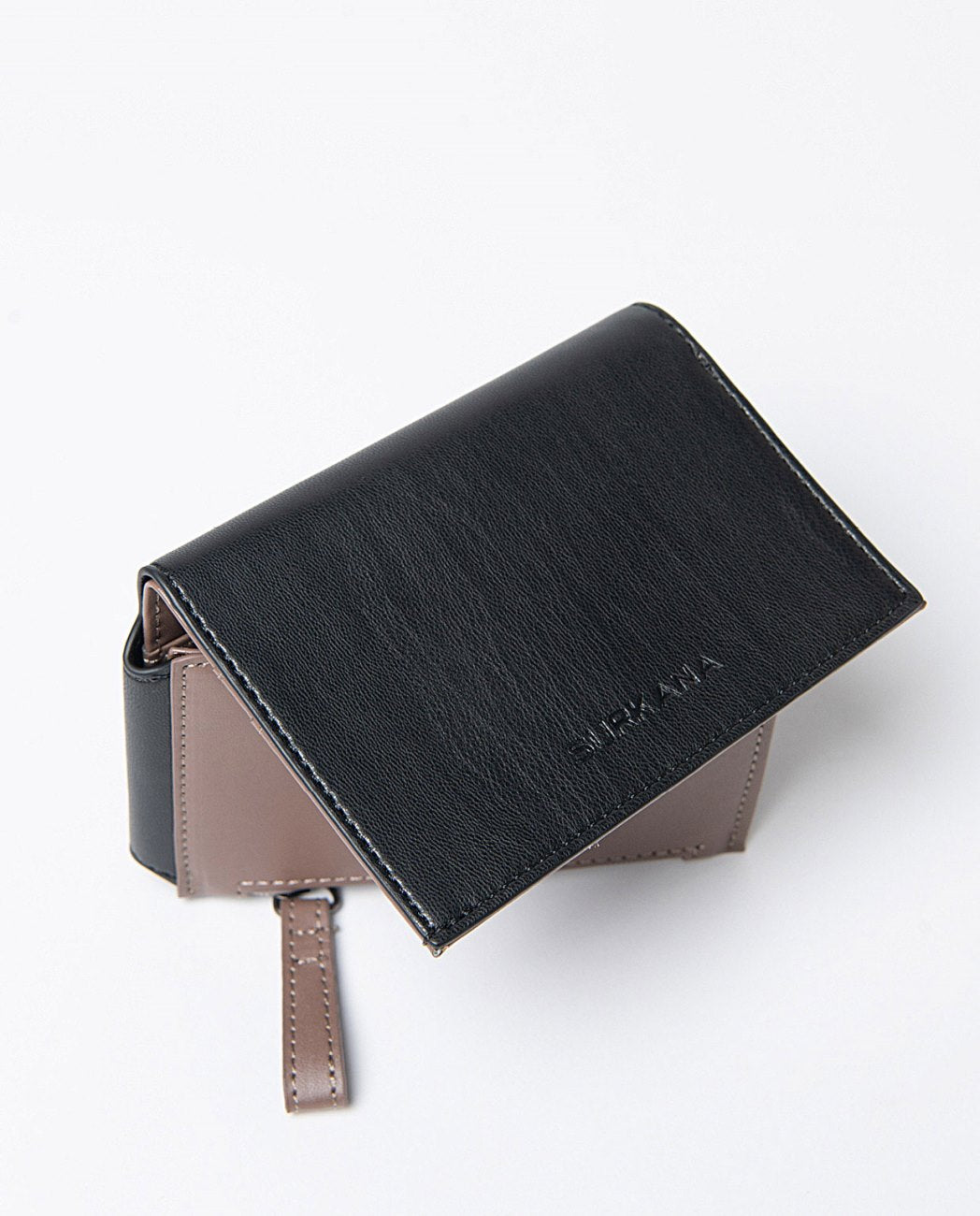 Small compact bi-color wallet in black and beige faux leather, includes compartments for cards, a zippered pocket and snap button closure. 