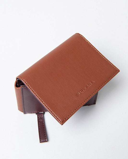 Small bi-color compact wallet in camel and chestnut faux leather, includes compartments for cards, a zippered pocket and snap button closure.