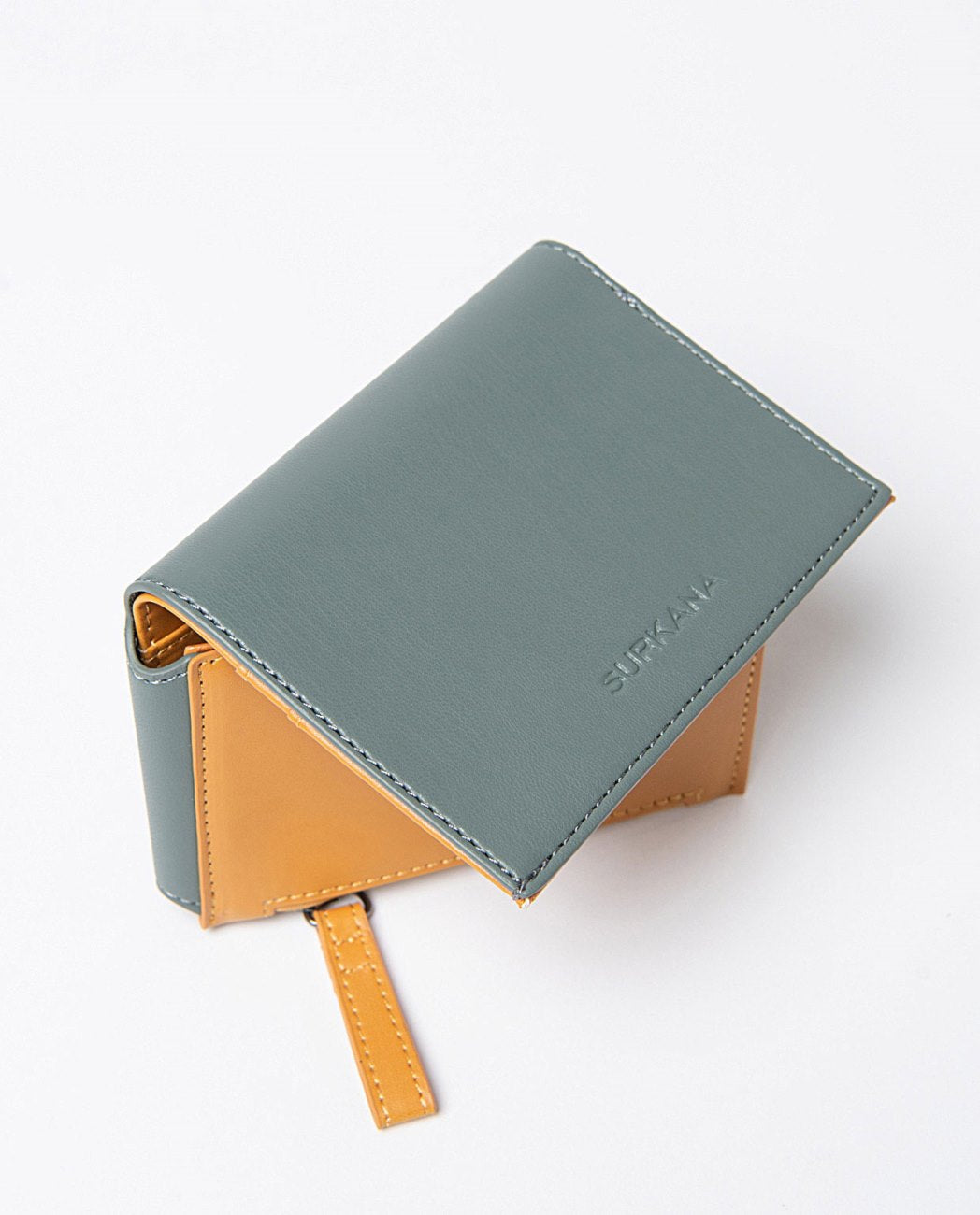 Small compact bi-color wallet in cobalt blue and yellow faux leather, includes compartments for cards, a zippered pocket and snap button closure. 