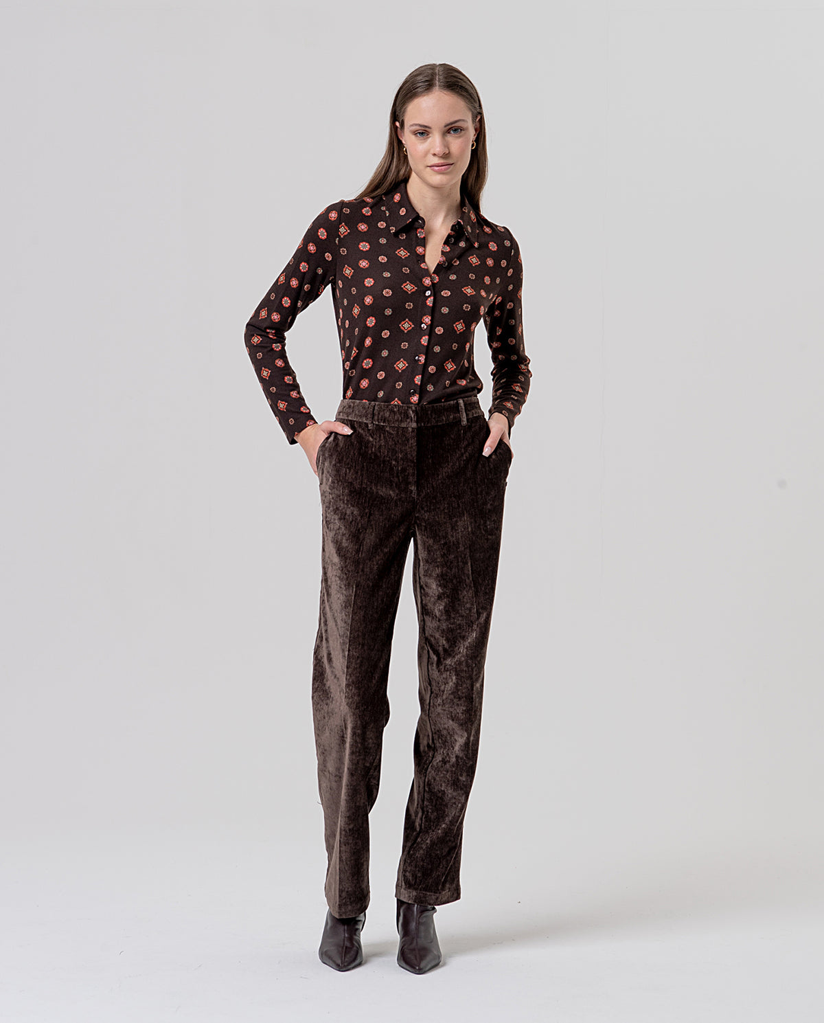 Straight-leg dark brown high-waisted trousers with belt loops and pockets, in velvet fabric with a soft feel and subtle sheen. Clean, flattering silhouette.