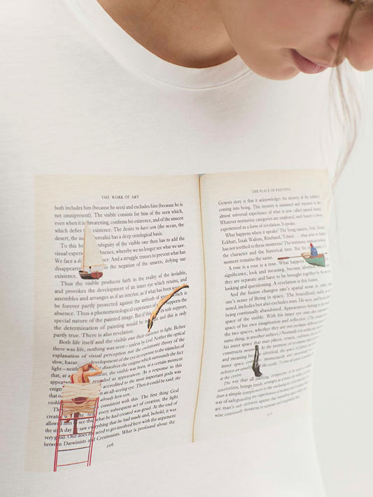 White cotton t-shirt with printed design of an open book and illustrations.