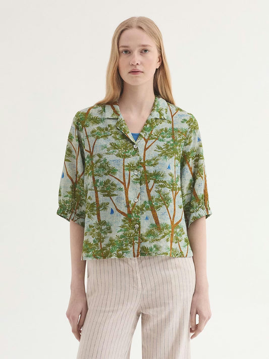 Pine Trees wood print shirt, ecru background color with blue like the sea and brown and green pine trees. notch lapels and button front, short sleeves with elasticated cuffs, in 50% Viscose, 50% Cotton