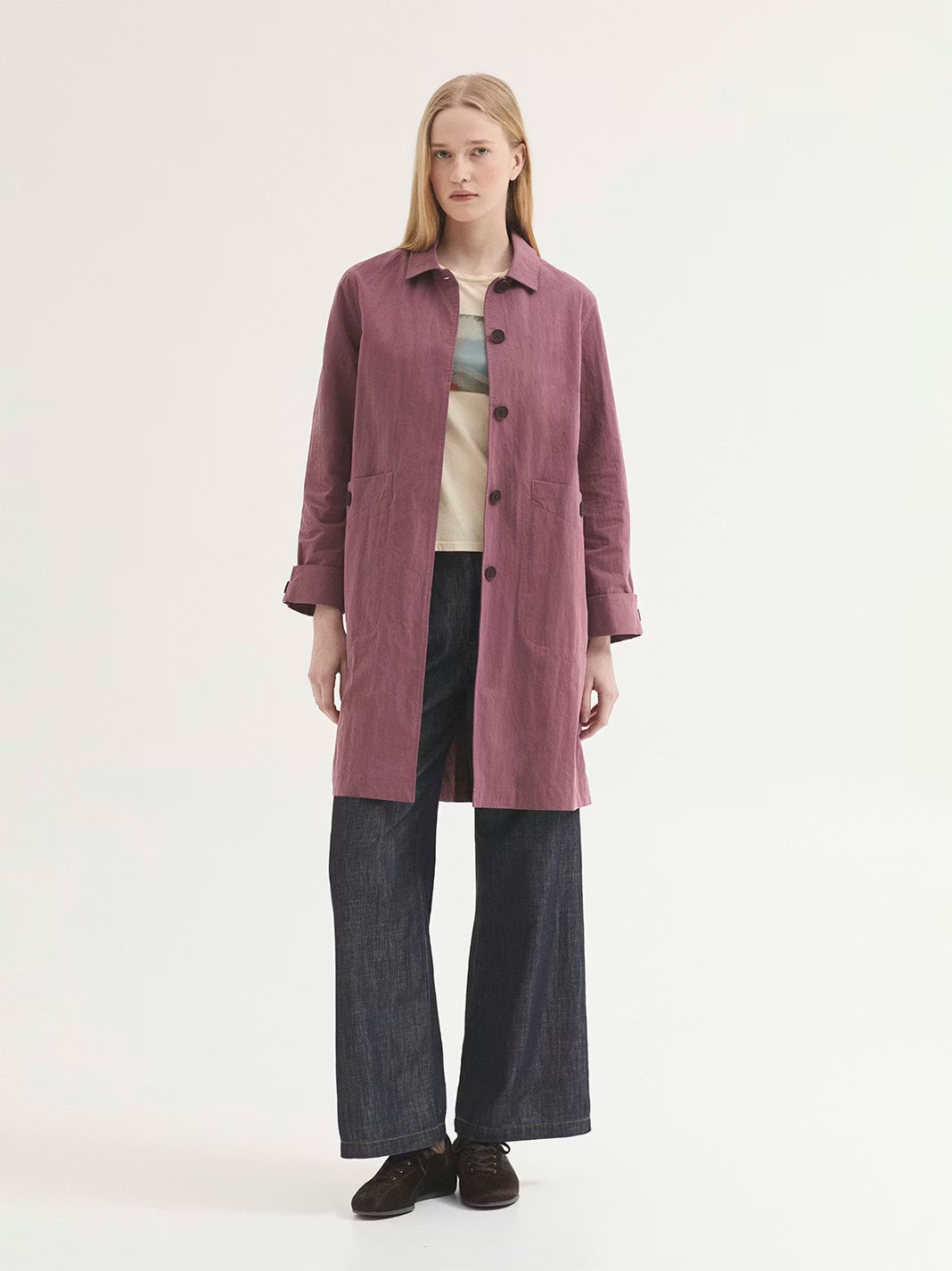 Water-resistant mauve trench coat made of cotton and nylon blend. Featuring a shirt collar, concealed button front and pockets with button. With vent and button at back, and sleeves with folded cuff and button.