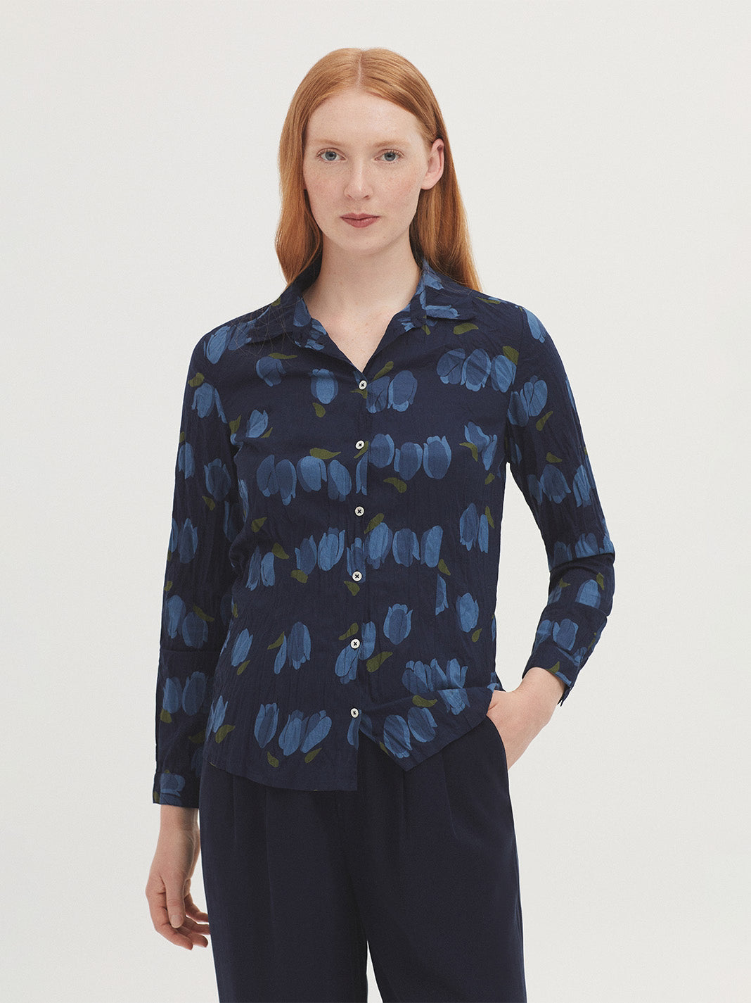 Basic navy shirt with light blue and olive green Tulips print in sustainable crinkle cotton fabric, shirt collar and mother-of-pearl button front, long sleeves with vent, cuff and button, complete with matching fabric bag.